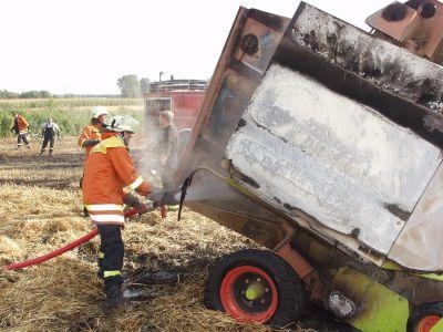 Strohbindermaschine setzt abgeerntetes Feld in Brand